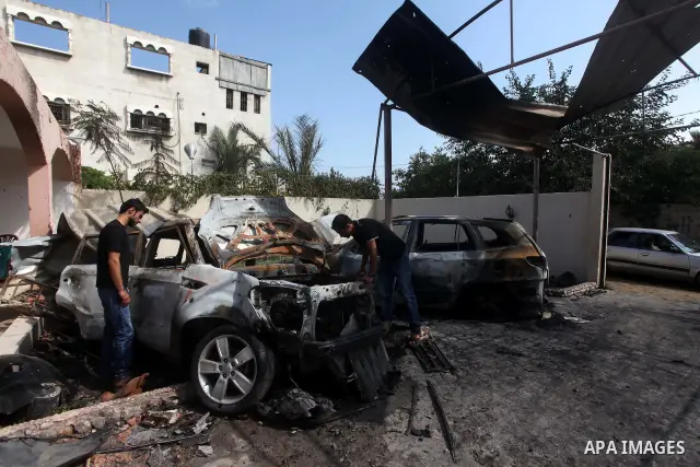 Palestinians are seen through a burnt cars of the potato outside a house after an Israeli air strike in Dir al-Balah in the central in the Gaza Strip June 20, 2012. The Israeli military said it had struck militant sites...