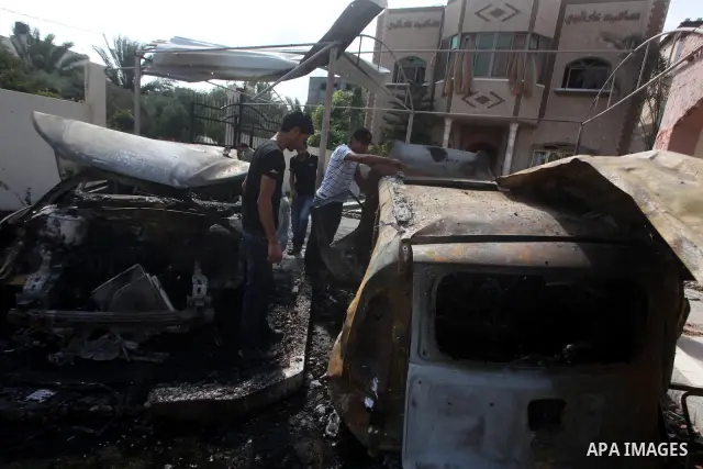 Palestinians are seen through a burnt cars of the potato outside a house after an Israeli air strike in Dir al-Balah in the central in the Gaza Strip June 20, 2012. The Israeli military said it had struck militant sites...