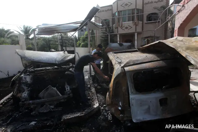 Palestinians are seen through a burnt cars of the potato outside a house after an Israeli air strike in Dir al-Balah in the central in the Gaza Strip June 20, 2012. The Israeli military said it had struck militant sites...