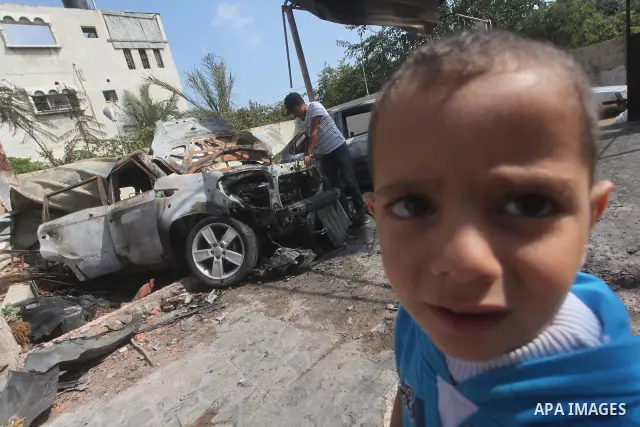 Palestinians are seen through a burnt cars of the potato outside a house after an Israeli air strike in Dir al-Balah in the central in the Gaza Strip June 20, 2012. The Israeli military said it had struck militant sites...