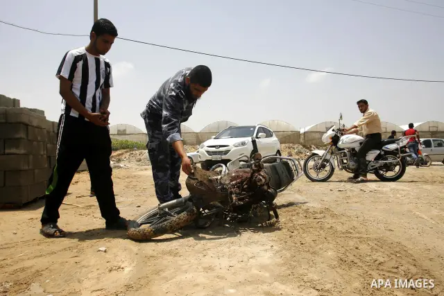 Palestinians look at the blood stained motorcycle riden by 21-year-old Ghaleb Ermilat, when he was killed in an Israeli military strike in Rafah, in the Gaza Strip on June 20, 2012. According to the Isreali military, the...