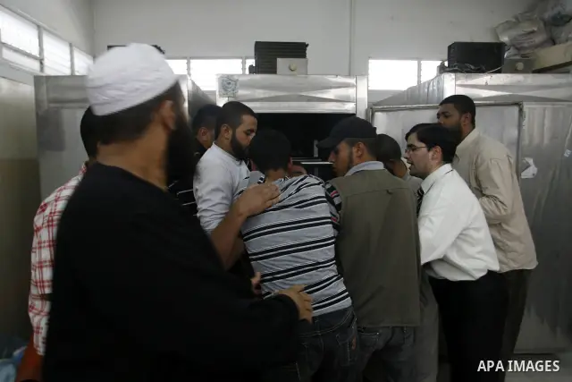 Palestinians look at the body of 21-year-old Ghaleb Ermilat, , at the morgue in the Al Najar hospital in Rafah, in the Gaza Strip on June 20, 2012. There was no let-up in rocket fire from Gaza with at least 10 hitting th...