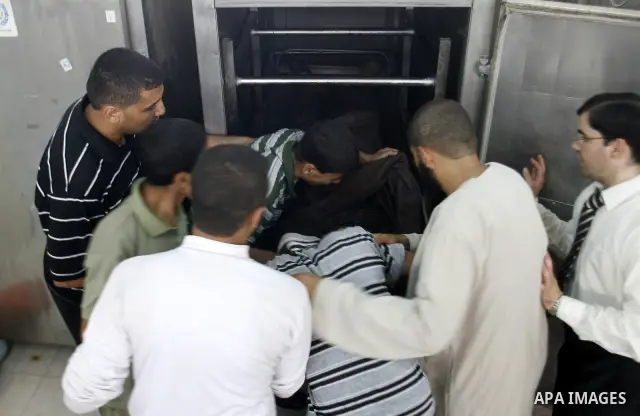 Palestinians look at the body of 21-year-old Ghaleb Ermilat, , at the morgue in the Al Najar hospital in Rafah, in the Gaza Strip on June 20, 2012. There was no let-up in rocket fire from Gaza with at least 10 hitting th...