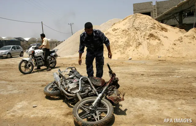 Palestinians look at the blood stained motorcycle riden by 21-year-old Ghaleb Ermilat, when he was killed in an Israeli military strike in Rafah, in the Gaza Strip on June 20, 2012. According to the Isreali military, the...