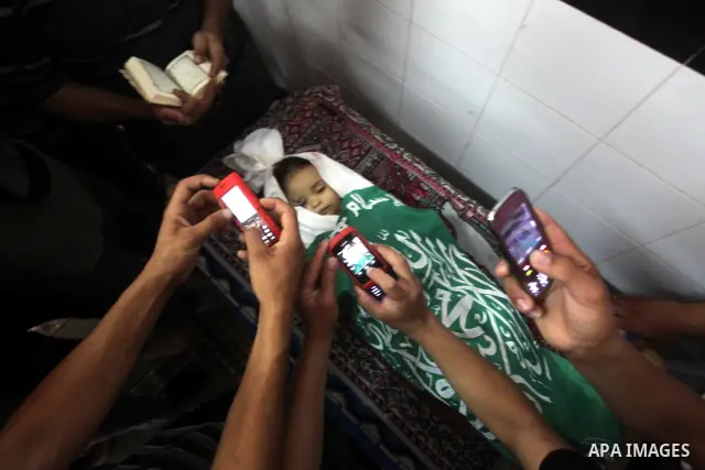 Palestinians take pictures to the body of two-year-old Hadeel al Hadad, after her funeral in Gaza City, Wednesday, June 20, 2012. Gaza health official Adham Abu Salmia said an explosion in a house killed al-Hadad and inj...