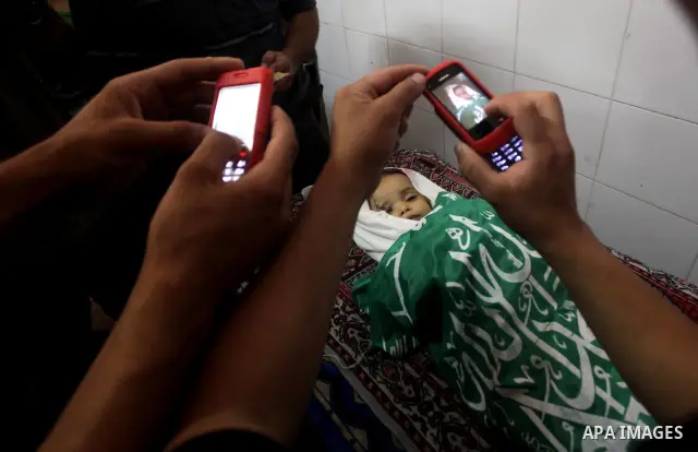 Palestinians take pictures to the body of two-year-old Hadeel al Hadad, after her funeral in Gaza City, Wednesday, June 20, 2012. Gaza health official Adham Abu Salmia said an explosion in a house killed al-Hadad and inj...