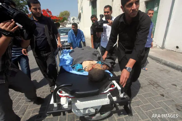 Palestinian men carry the body of Moamen al-Adam, 14, to the morgue of Al-Shifa hospital in Gaza City on June 20, 2012 after he was killed and his father Zohde Al-Dam in an Israeli air strike raising to eight the number...