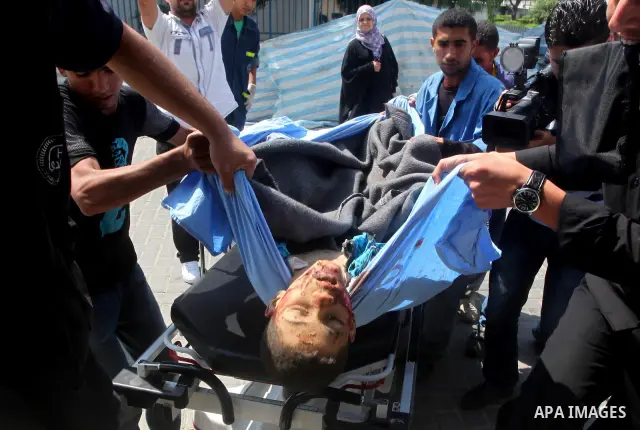 Palestinian men carry the body of Moamen al-Adam, 14, to the morgue of Al-Shifa hospital in Gaza City on June 20, 2012 after he was killed and his father Zohde Al-Dam in an Israeli air strike raising to eight the number...