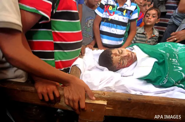 Friends of 14-year old Palestinian Moamen al-Adam, who was killed in an Israeli air strike the day before, bids farewell to him during his funeral procession in Gaza city on June 21, 2012. The latest attacks follow three...