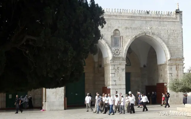 Israeli Jewish settlers walk in front of al-Aqsa Mosque as Palestinians children participate in summer camps in the old city of Jerusalem on 21 June 2012. Photo by Mahfouz Abu Turk