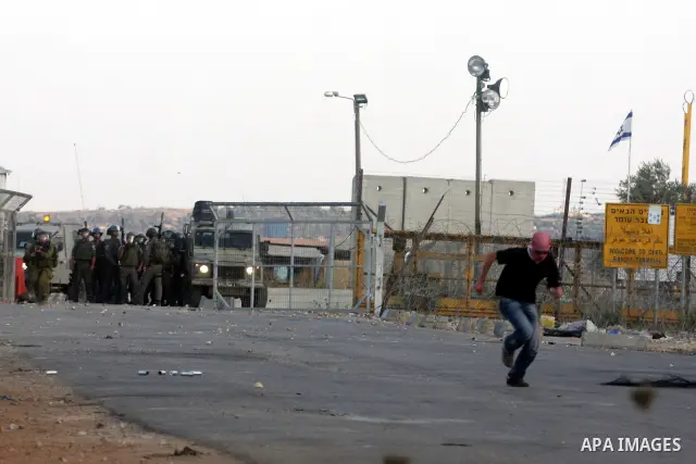 A Palestinian protestor takes cover during clashes with Israeli police following a demonstration outside Ofer prison, near the West Bank city of Ramallah, in solidarity with Palestinian prisoners being held in Israeli ja...