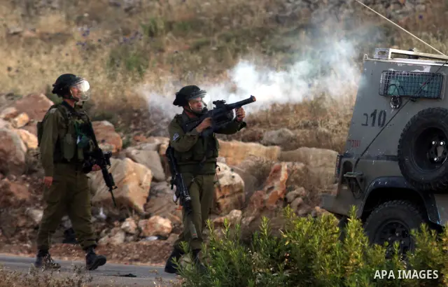 An Israeli soldier shoots tear gas at Palestinian protestors during clashes following a demonstration outside Ofer prison, near the West Bank city of Ramallah, in solidarity with Palestinian prisoners being held in Israe...