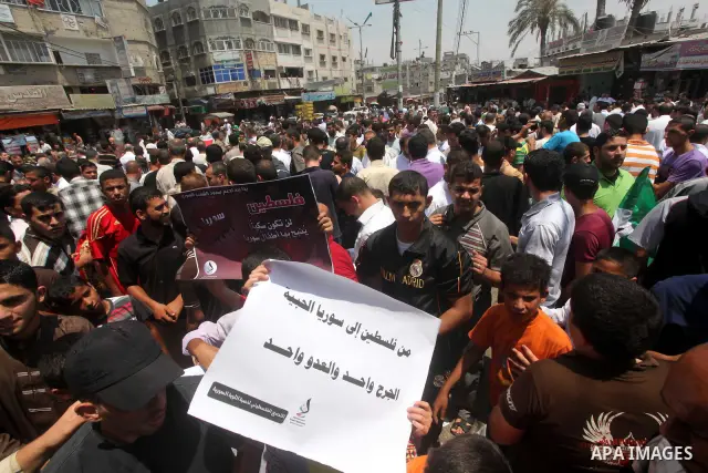 Palestinians hold a Syrian revolution flag during a protest against Syria's President Bashar al-Assad and in support of Syrian civilians at Nusseirat refugee camp in the central Gaza Strip on June 22, 2012. The French fo...