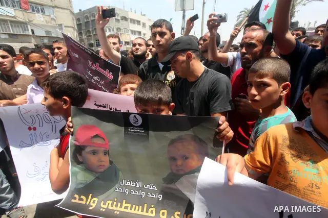 Palestinians hold a Syrian revolution flag during a protest against Syria's President Bashar al-Assad and in support of Syrian civilians at Nusseirat refugee camp in the central Gaza Strip on June 22, 2012. The French fo...