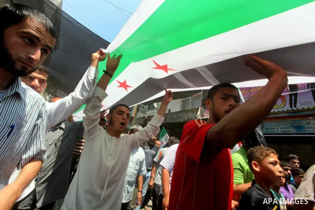 Palestinians hold a Syrian revolution flag during a protest against Syria's President Bashar al-Assad and in support of Syrian civilians at Nusseirat refugee camp in the central Gaza Strip on June 22, 2012. The French fo...