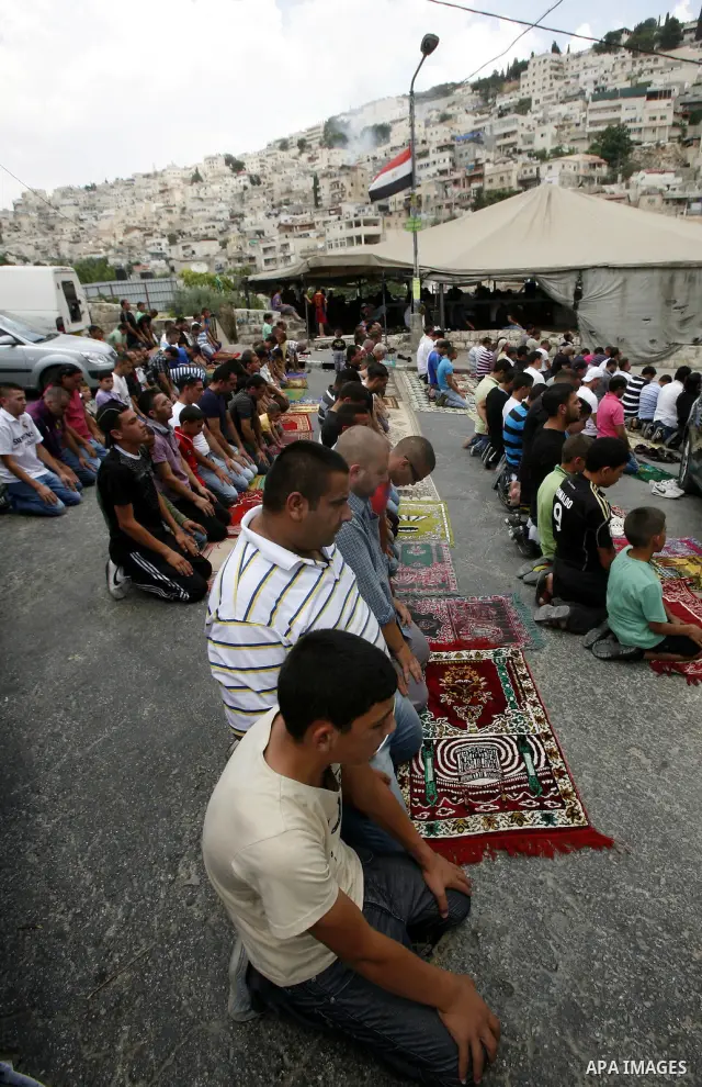 Palestinian Muslim worshippers attend Friday prayers outside a protest tent against the continuing 'Judaization of Jerusalem' by Jewish settlers, in the mostly Arab neighbourhood of Silwan in east Jerusalem on June 22, 2...