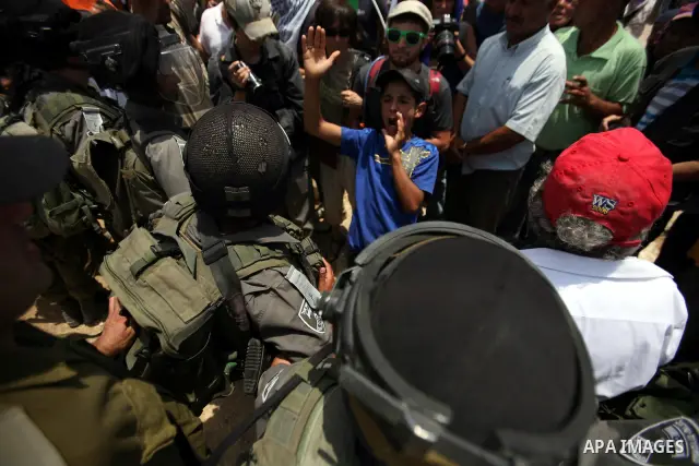 Foreign activists and Palestinians dressed as clowns gesture in front of Israeli policemen during a protest in the southern West Bank village of Susia near Hebron city on June 22, 2012 where Israel has recently served or...