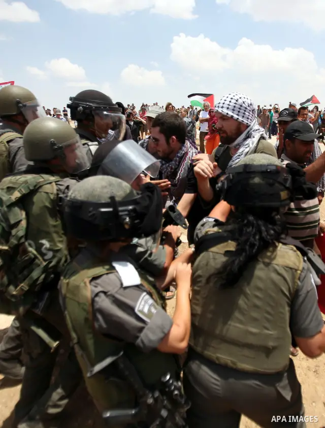 Foreign activists and Palestinians dressed as clowns gesture in front of Israeli policemen during a protest in the southern West Bank village of Susia near Hebron city on June 22, 2012 where Israel has recently served or...