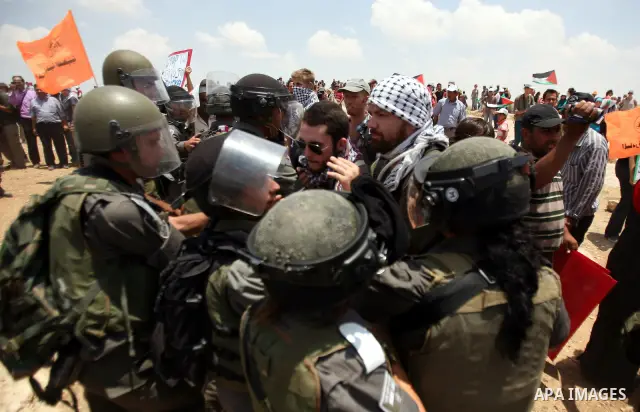Foreign activists and Palestinians dressed as clowns gesture in front of Israeli policemen during a protest in the southern West Bank village of Susia near Hebron city on June 22, 2012 where Israel has recently served or...