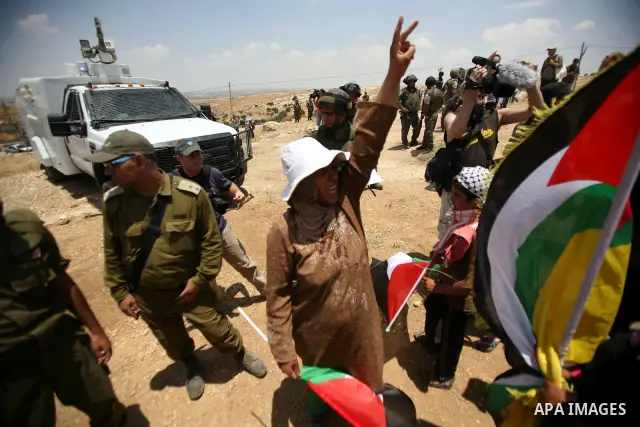 Foreign activists and Palestinians dressed as clowns gesture in front of Israeli policemen during a protest in the southern West Bank village of Susia near Hebron city on June 22, 2012 where Israel has recently served or...