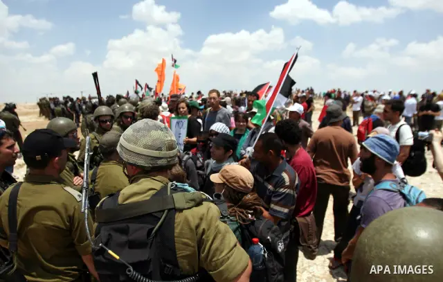 Foreign activists and Palestinians dressed as clowns gesture in front of Israeli policemen during a protest in the southern West Bank village of Susia near Hebron city on June 22, 2012 where Israel has recently served or...