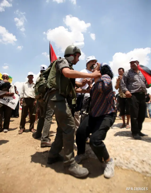 An Israeli policeman pulls away a Palestinian activist during a protest in the southern West Bank village of Susia on June 22, 2012 where Israel has recently served orders to evacuate and demolish 50 structures comprisin...