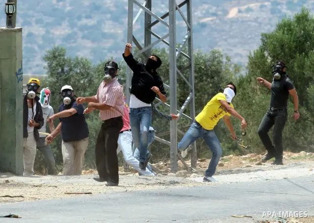 Palestinian demonstrators throw stones during clashes following a weekly protest against the Jewish settlement of Kdumim, near Nablus,in the northern West Bank village of Kufr Qaddum, June 22, 2012. According to medical...