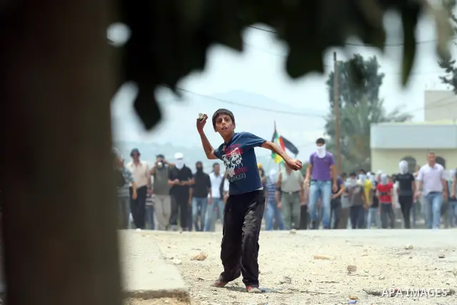 A Palestinian demonstrator throws stones during clashes following a weekly protest against the Jewish settlement of Kdumim, near Nablus,in the northern West Bank village of Kufr Qaddum, June 22, 2012. According to medica...