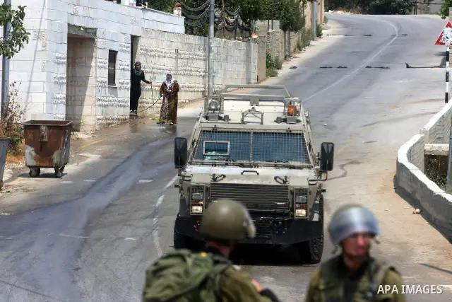 Palestinian women look at the Israeli soldiers during clashes with Palestinian protesters in the West Bank village of Nabi Saleh, near Ramallah, on June 22, 2012, following a demonstration against the confiscation of Pal...