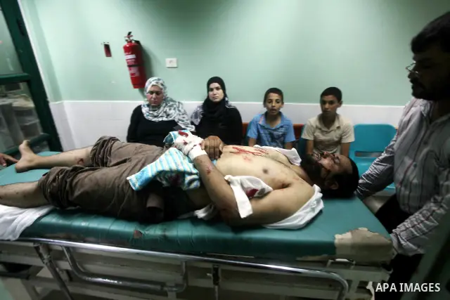 Palestinian medics wheel a wounded man to the treatment room of Al-Aqsa hospital following an Israeli airstrike east of Bureij refugee camp, in Deir Al Balah, central Gaza strip, Friday, June 22, 2012. An Israeli air str...