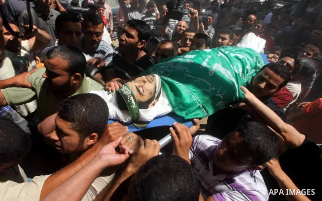 Palestinians carry the body of Hamas militant Hamam Abu Qadus during his funeral in Gaza City June 23, 2012. Israel launched air raids early on Saturday against three Hamas security targets in the Gaza Strip, wounding at...