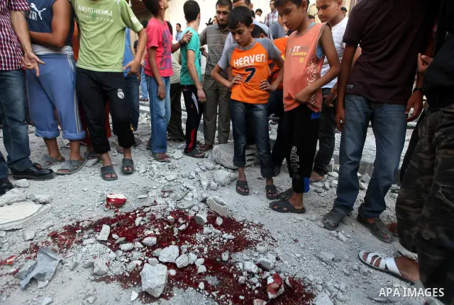 Palestinian children stand looking at the blood stained street following an Israeli strike on Gaza City on June 23, 2012. A Palestinian teenager riding a motorcycle was killed and 10 passers-by wounded in a fresh Israeli...