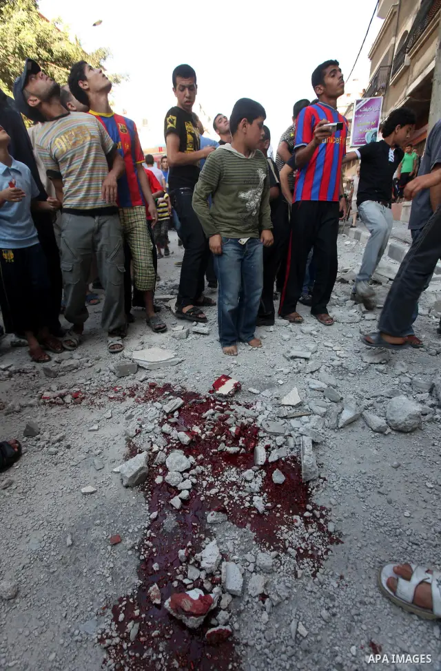 Palestinian children stand looking at the blood stained street following an Israeli strike on Gaza City on June 23, 2012. A Palestinian teenager riding a motorcycle was killed and 10 passers-by wounded in a fresh Israeli...
