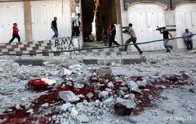 Palestinian children stand looking at the blood stained street following an Israeli strike on Gaza City on June 23, 2012. A Palestinian teenager riding a motorcycle was killed and 10 passers-by wounded in a fresh Israeli...