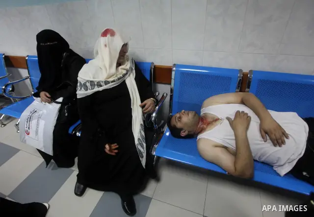 A Palestinian woman and man sit wounded in the emergency room of a hospital following an Israeli strike on Gaza City on June 23, 2012. A Palestinian teenager riding a motorcycle was killed, and 10 passers-by wounded in a...