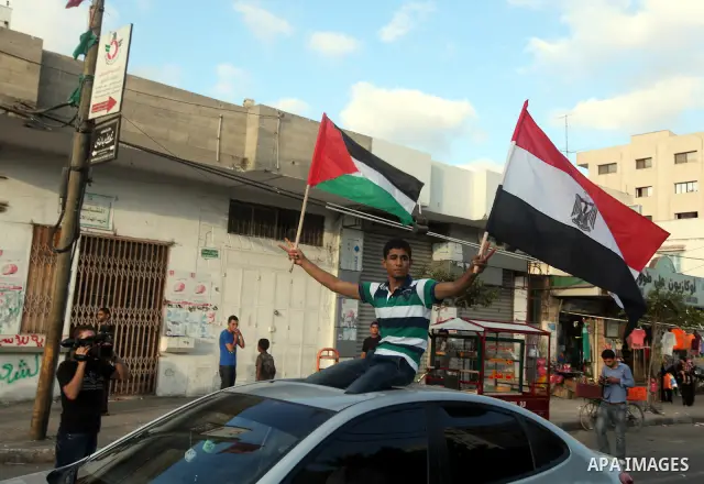 Palestinians hold national and Egyptian flags as they celebrate in Gaza City, the victory of Muslim Brotherhood's presidential candidate, Mohamed Morsi, in the Egyptian elections on June 24, 2012. Arab governments and le...
