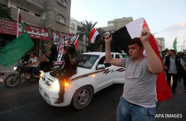 Hamas militants hold a poster depicting Mohamed Morsy of the Muslim Brotherhood as they celebrate in the street in Gaza City after he was declared Egypt's first democratic president June 24, 2012. Morsy's win was hailed...