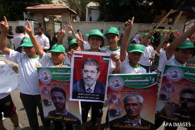 Palestinian boys supporter hold up images for Mohamed Morsi's and palestinian prisoners during celebrations after Muslim Brotherhood's presidential candidate Mohamed Morsi's victory in the Egyptian elections. Palestinian...