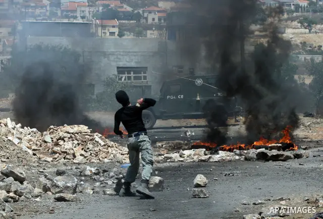 A Palestinian protestor throws stones during clashes with Israeli troops following a weekly protest against the Jewish settlement of Kdumim, near Nablus,in the northern West Bank village of Kufr Qaddum, June 29, 2012. Ph...