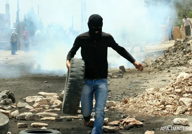 A Palestinian protestor sets a tyre on fire during clashes with Israeli troops following a weekly protest against the Jewish settlement of Kdumim, near Nablus,in the northern West Bank village of Kufr Qaddum, June 29, 20...