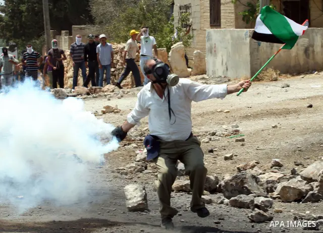 A Palestinian Protestor throws back a tear gas canister towards Israeli troops during clashes following a weekly protest against the Jewish settlement of Kdumim, near Nablus,in the northern West Bank village of Kufr Qadd...