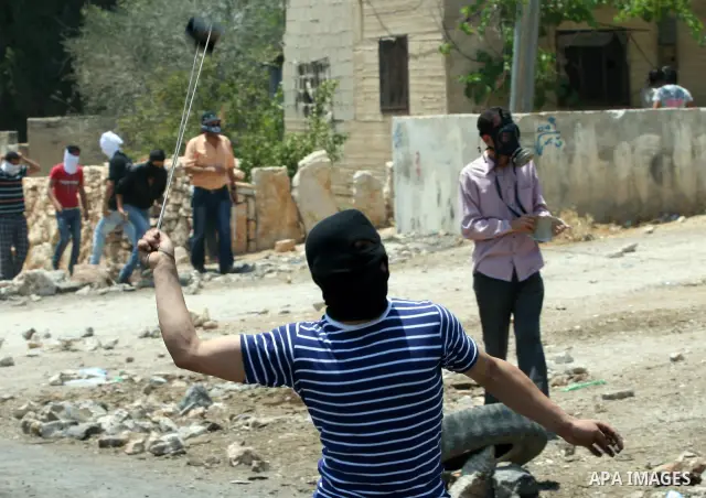 A Palestinian protestor throws stones during clashes with Israeli troops following a weekly protest against the Jewish settlement of Kdumim, near Nablus,in the northern West Bank village of Kufr Qaddum, June 29, 2012. Ph...