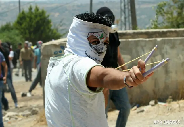 A Palestinian protestor throws stones during clashes with Israeli troops following a weekly protest against the Jewish settlement of Kdumim, near Nablus,in the northern West Bank village of Kufr Qaddum, June 29, 2012. Ph...