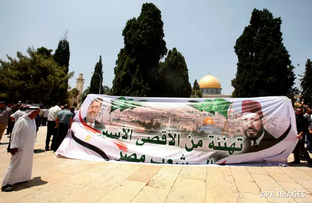 Palestinians hold up a banner with pictures for Egyptian President-elect Mohammed Morsi (L) and Sheikh Hasan al-Bana (R) founder of Muslim Brotherhood, in front of al-Aqsa Mosque on 29 June 2012, during a rally in the ol...