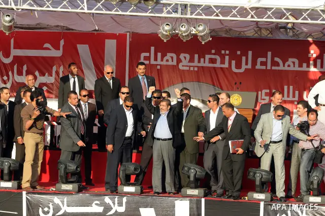Egypt's president-elect Mohamed Morsi, surrounded by security guards, waves to protesters at the end of his speech at Tahrir square, in Cairo, Egypt, 29 June 2012. Media reports stated Morsi said on 29 June that people p...