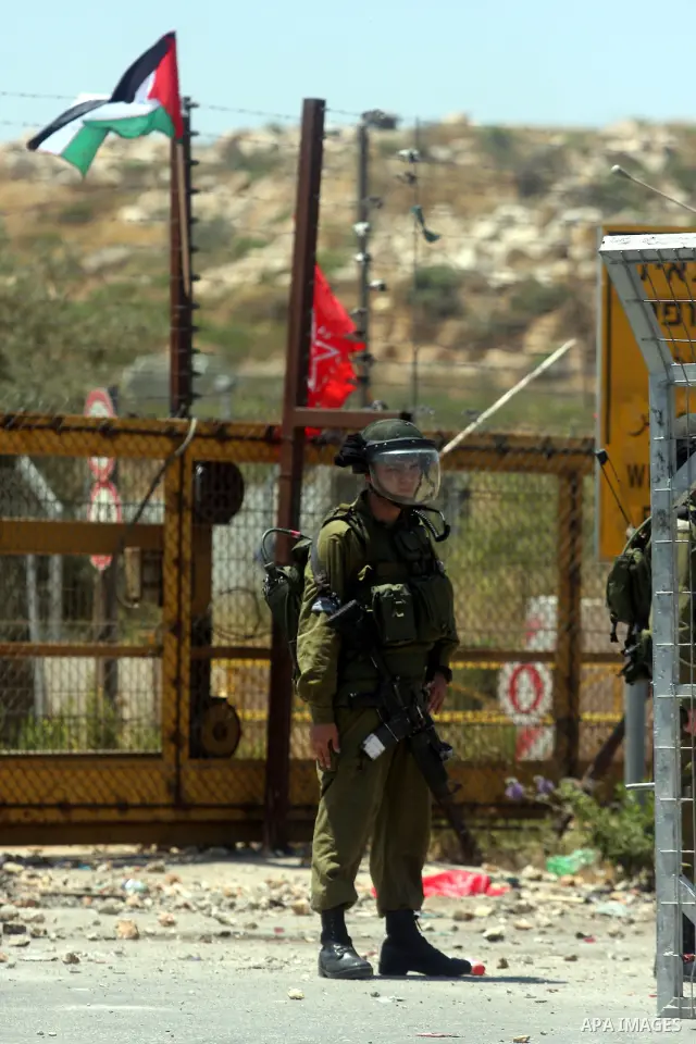 An Israeli soldier takes cover during clashes with Palestinian protestors following a demonstration outside Ofer prison, near the West Bank city of Ramallah,on Sunday, July, 1, 2012. Photo by Issam Rimawi
