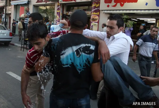 Palestinians help a wounded man, injured in a protest against a scheduled meeting between Palestinian President Mahmoud Abbas and the Israeli Vice Prime Minister Shaul Mofaz in the West Bank city of Ramallah, on 01 July...