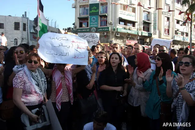 Palestinian protestors hold banners and national flags during a protest against a scheduled meeting between Palestinian President Mahmoud Abbas and the Israeli Vice Prime Minister Shaul Mofaz in the West Bank city of Ram...