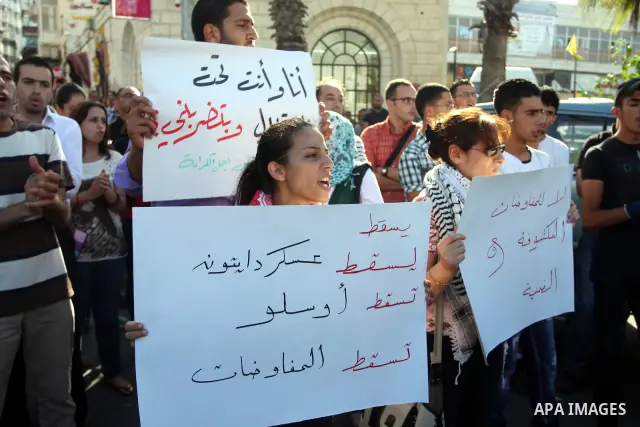 Palestinian protestors hold banners and national flags during a protest against a scheduled meeting between Palestinian President Mahmoud Abbas and the Israeli Vice Prime Minister Shaul Mofaz in the West Bank city of Ram...