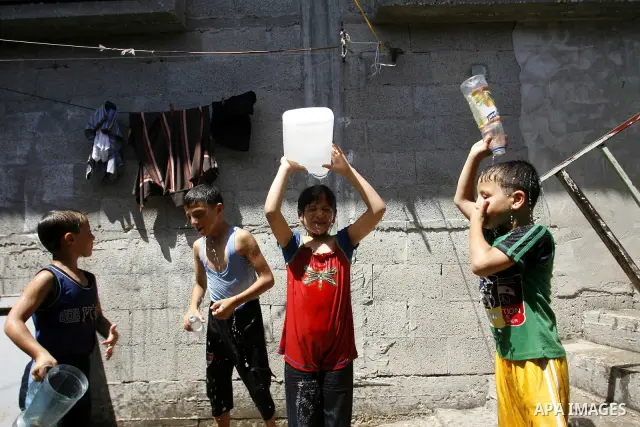 Palestinian children enjoy themselves with water during hot weather and high temperature in the southern Gaza Strip town of Rafah on July 02, 2012. Photo by Eyad Al Baba